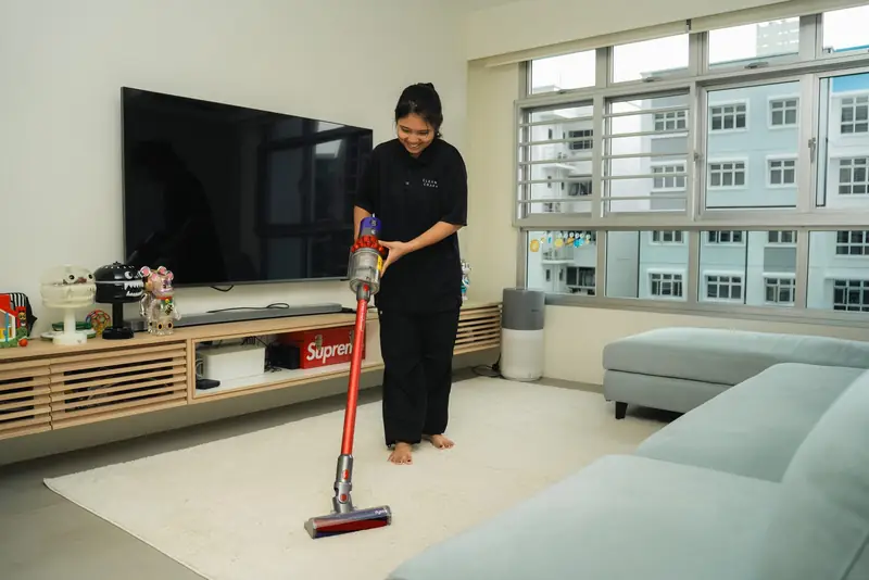 A Cleancraft cleaner vacuuming a bright HDB living room